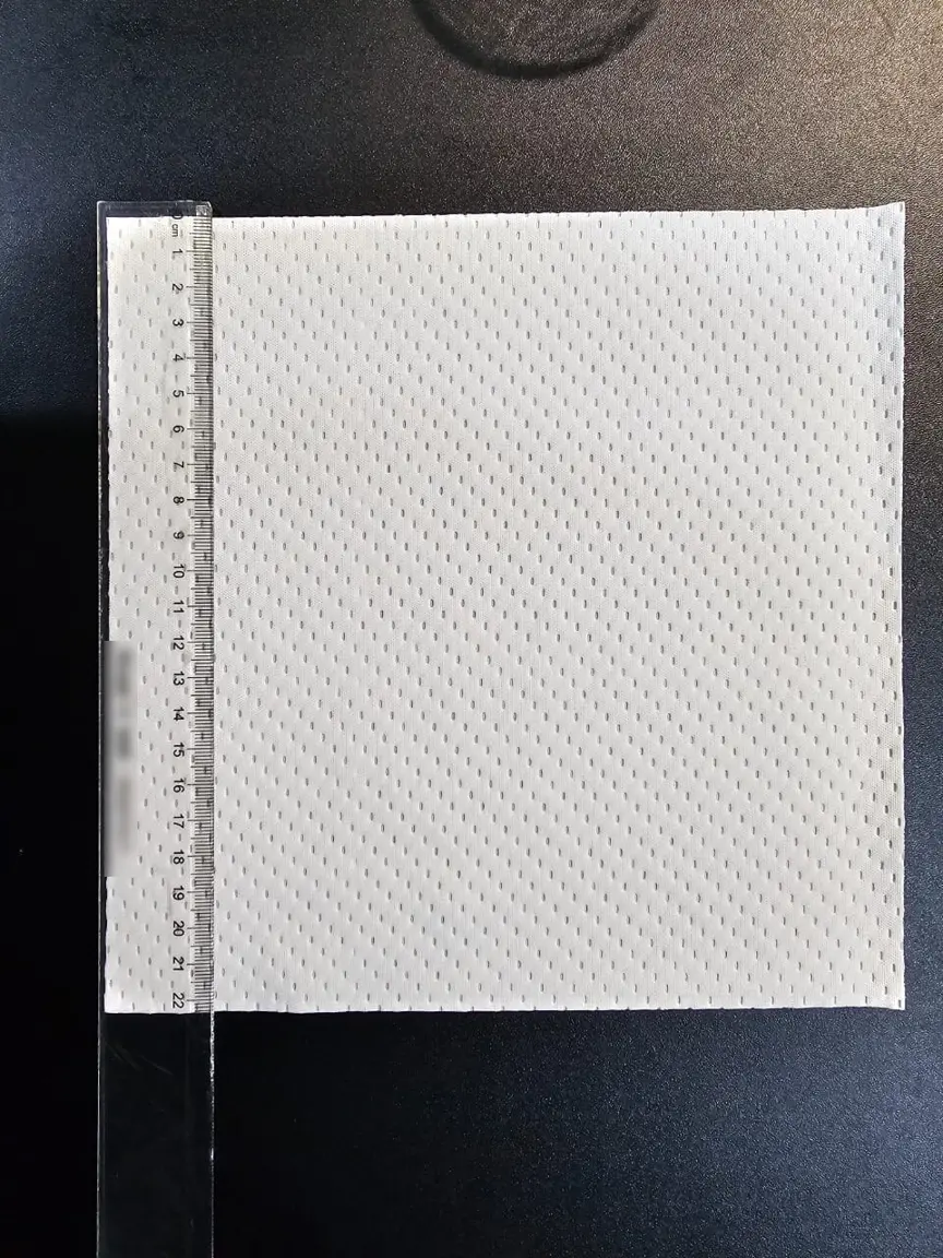 Square sheet of white 2-ply fabric with an even dot pattern, measured against a ruler at about 22 cm