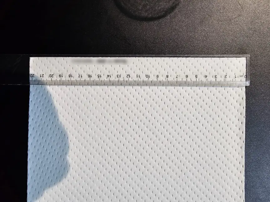 The same white 2-ply fabric sample measured across its width with a ruler