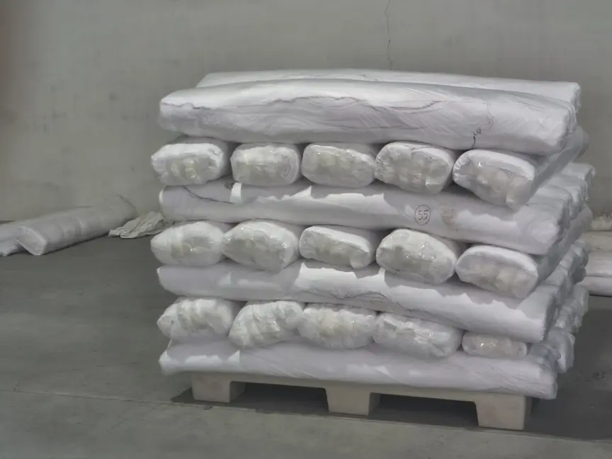 Finished fabric rolls, individually wrapped in plastic and stacked on a pallet ready for dispatch