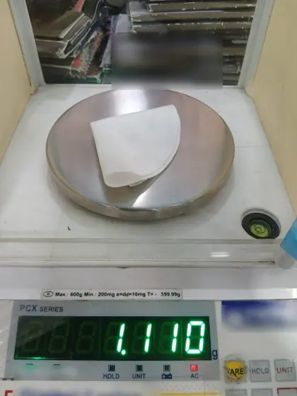 Circular fabric test sample on a precision scale reading 1.11 g