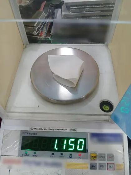 Circular fabric test sample on a precision scale reading 1.15 g